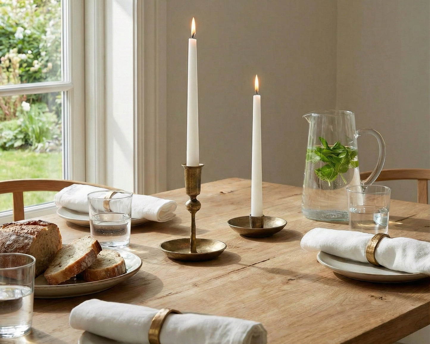 Rustic wooden table set with lit candles, bread, water pitcher, and napkins for cozy van life dining