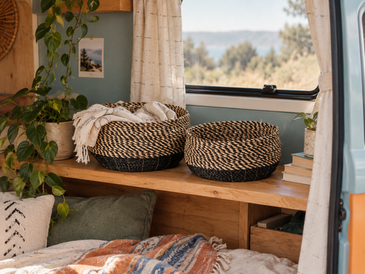Natural and black seagrass baskets on a timber shelf inside a campervan