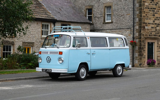 Blue campervan parked beside stone cottages in the Midlands