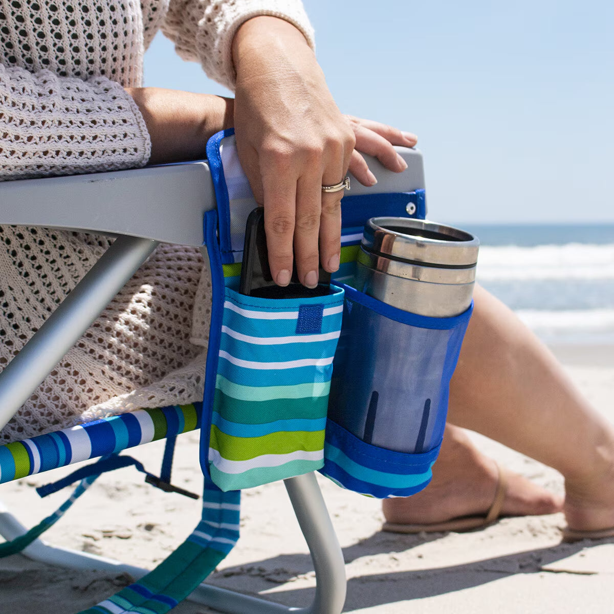 Beach chair side pocket holding phone and travel mug, perfect for van life and outdoor adventures