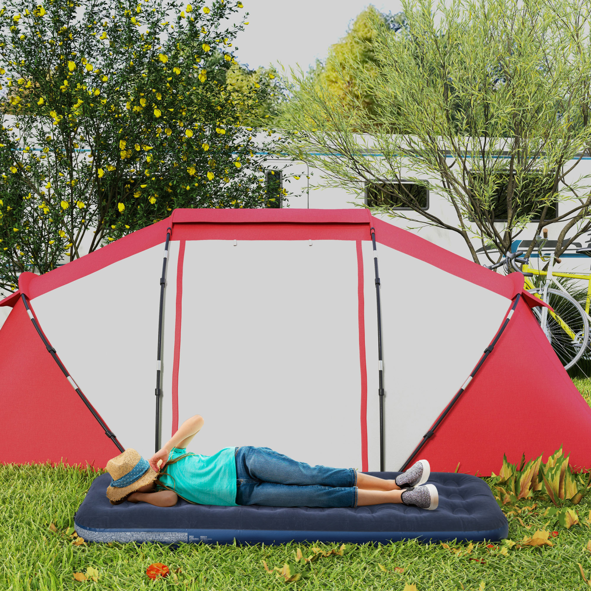Child relaxing on inflatable air mattress under red and white camping tent in grassy yard near camper van