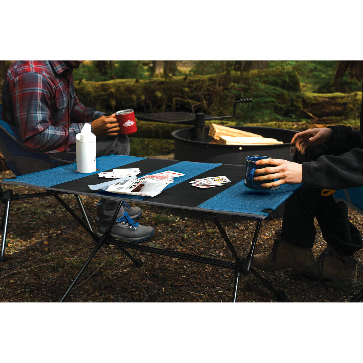 Portable camping table with blue and black surface, perfect for van life and outdoor adventures with cards and mugs.