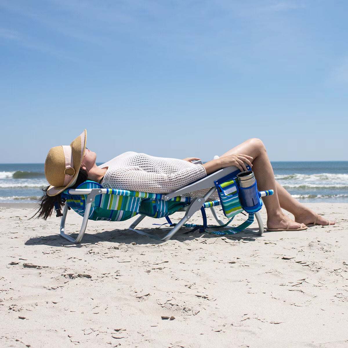 Woman relaxing on striped beach chair with cup holder, perfect for van life and outdoor adventures
