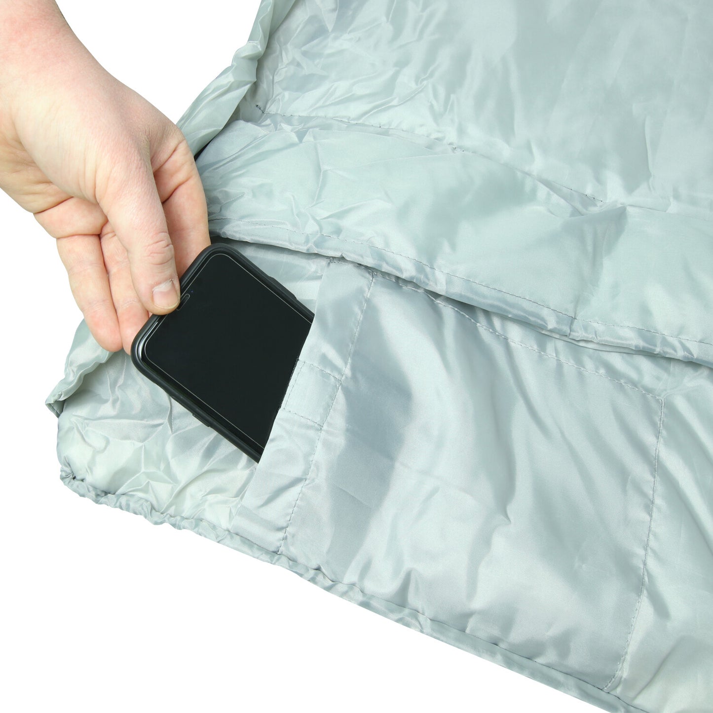 Hand placing phone into pocket of light grey quilted van mattress for van life comfort