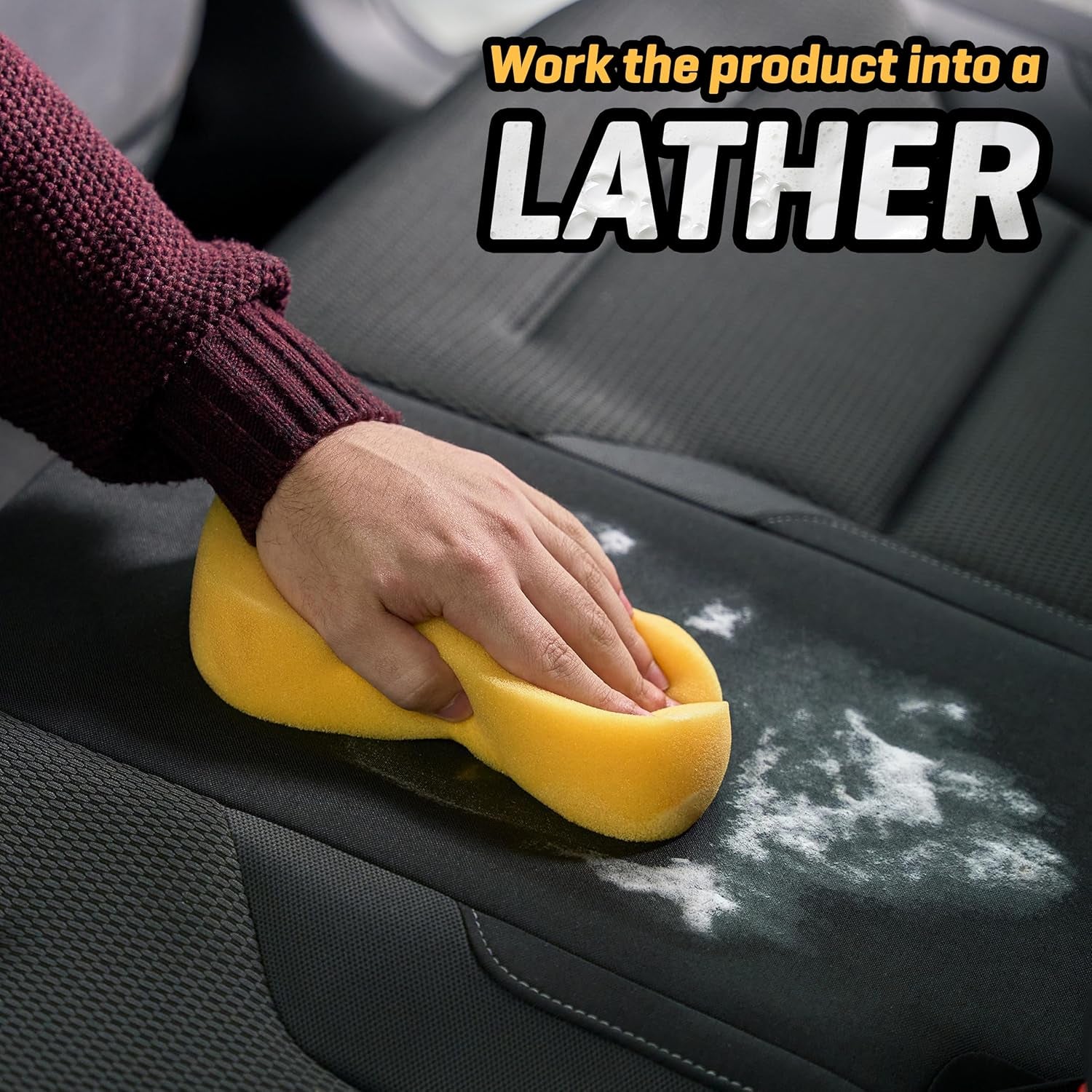Hand using yellow sponge to lather cleaner on black van seat, ideal for camper van interior care