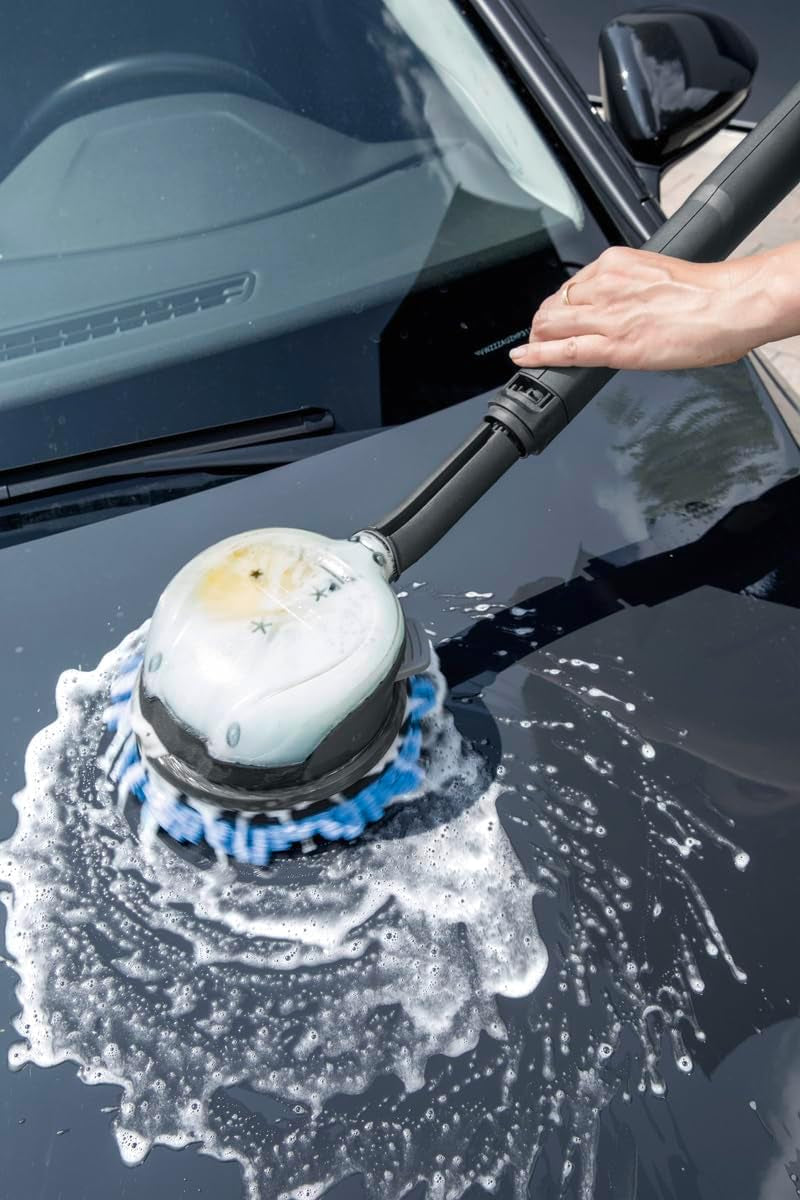 Hand using electric car wash brush with soap suds on black van hood, perfect for van life maintenance