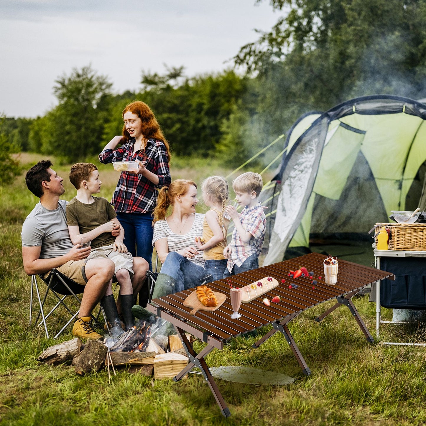 Family camping with portable table, foldable chairs, tent, and campfire in outdoor adventure setting
