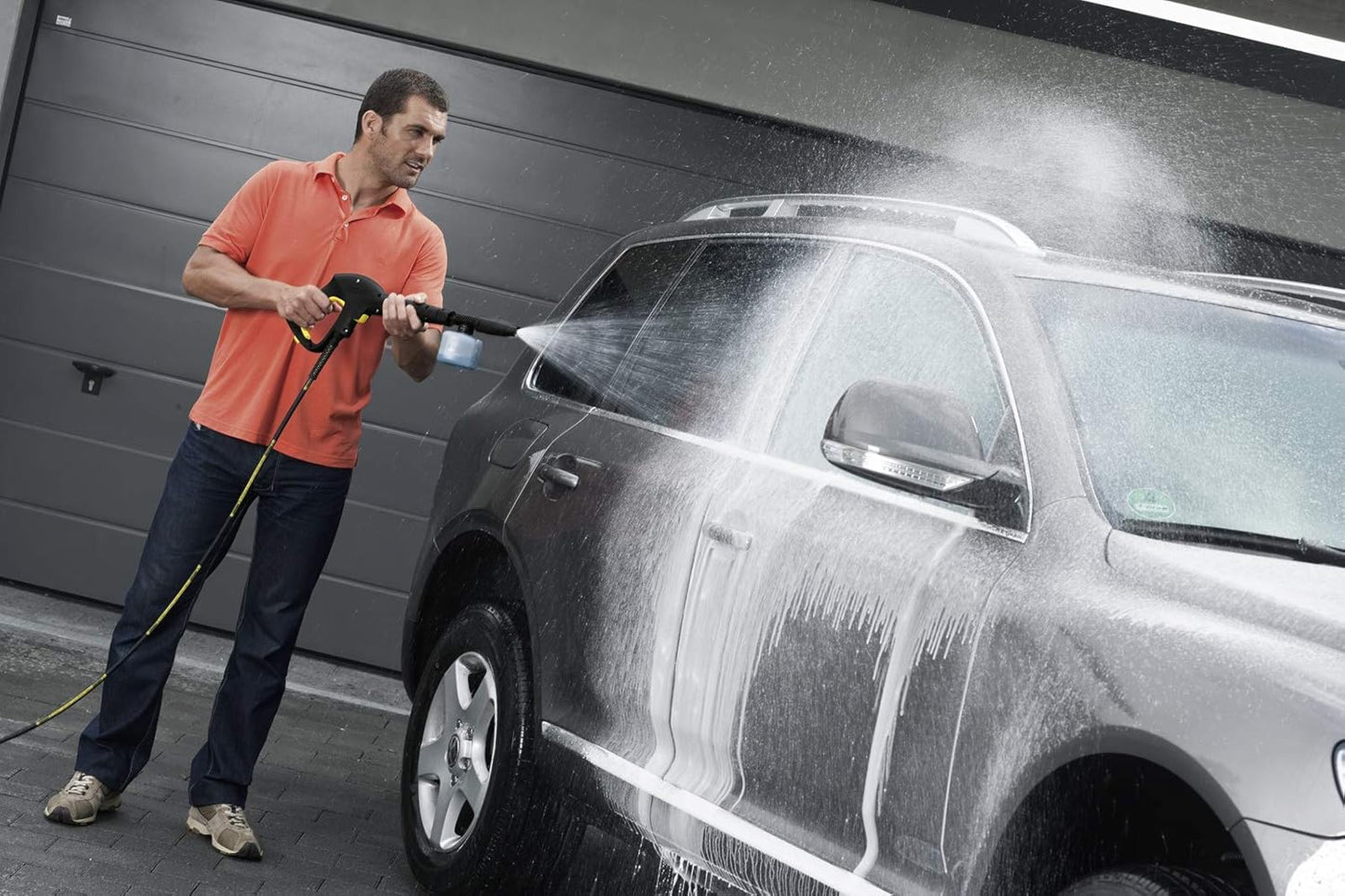 Man washing SUV with pressure washer, ideal for van life & outdoor adventures