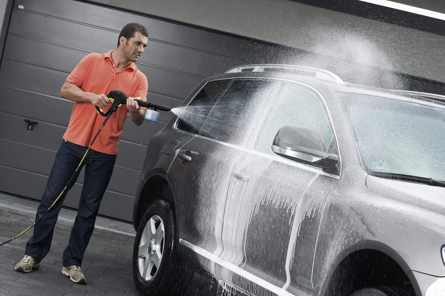 Man washing SUV with pressure washer, ideal for van life & outdoor adventures