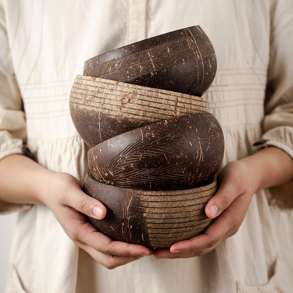 Hand holding stack of carved coconut bowls for van life camping and outdoor adventures