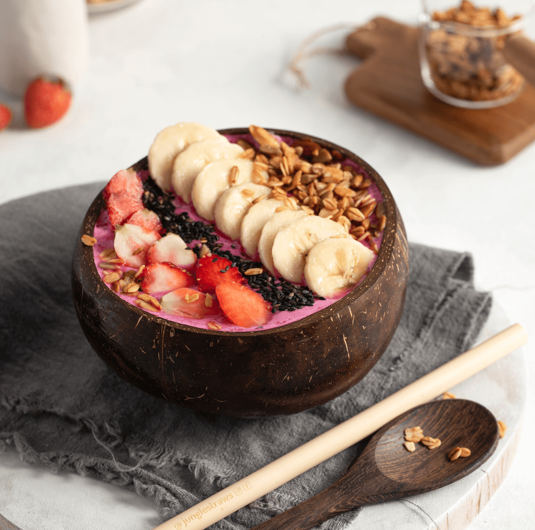 Coconut bowl with pink smoothie, banana, strawberries, granola, and seeds — van life breakfast essentials