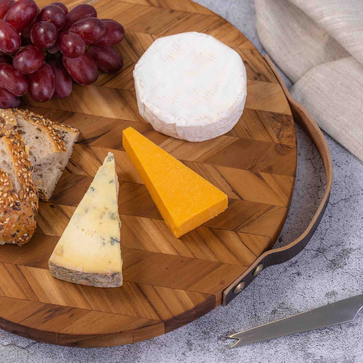 Wooden cheese board with assorted cheeses, grapes, and seeded bread for van life picnics and outdoor adventures