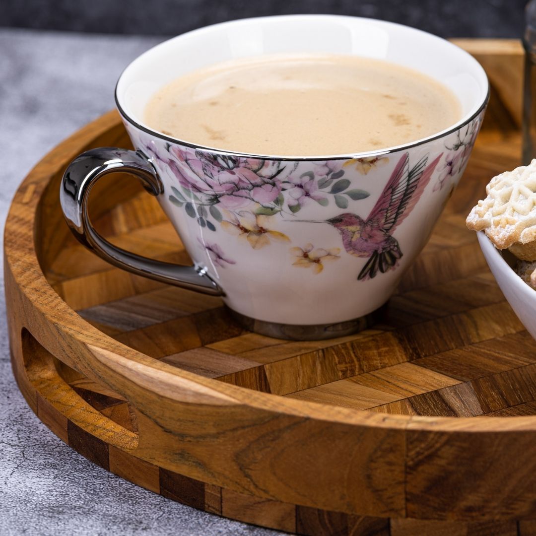 Floral hummingbird teacup with coffee on wooden tray, perfect for van life cozy moments
