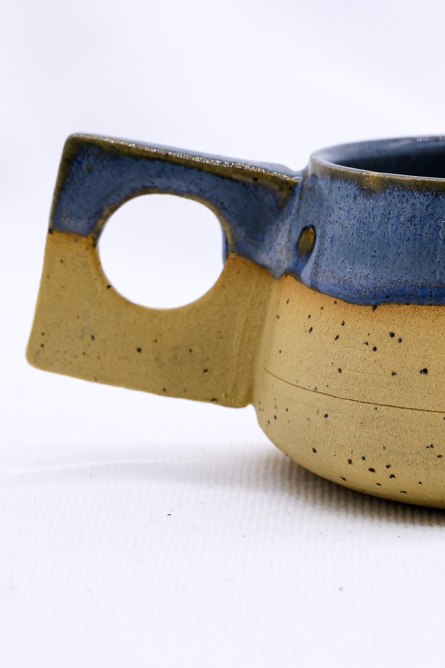 Handmade ceramic mug with blue glaze and square handle, perfect for van life adventures and outdoor camping.