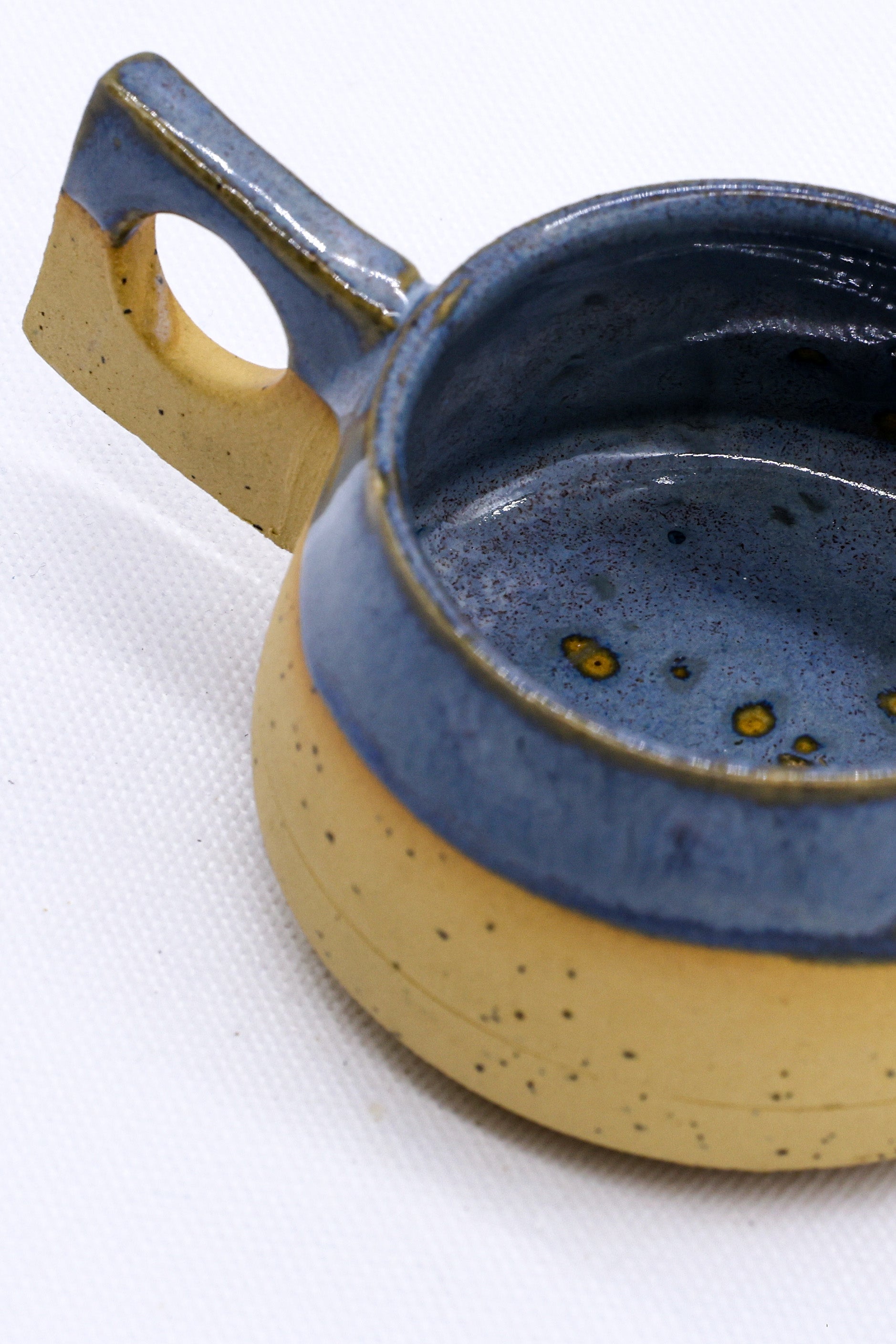 Handmade ceramic mug with blue glaze and speckled tan base, perfect for van life adventures