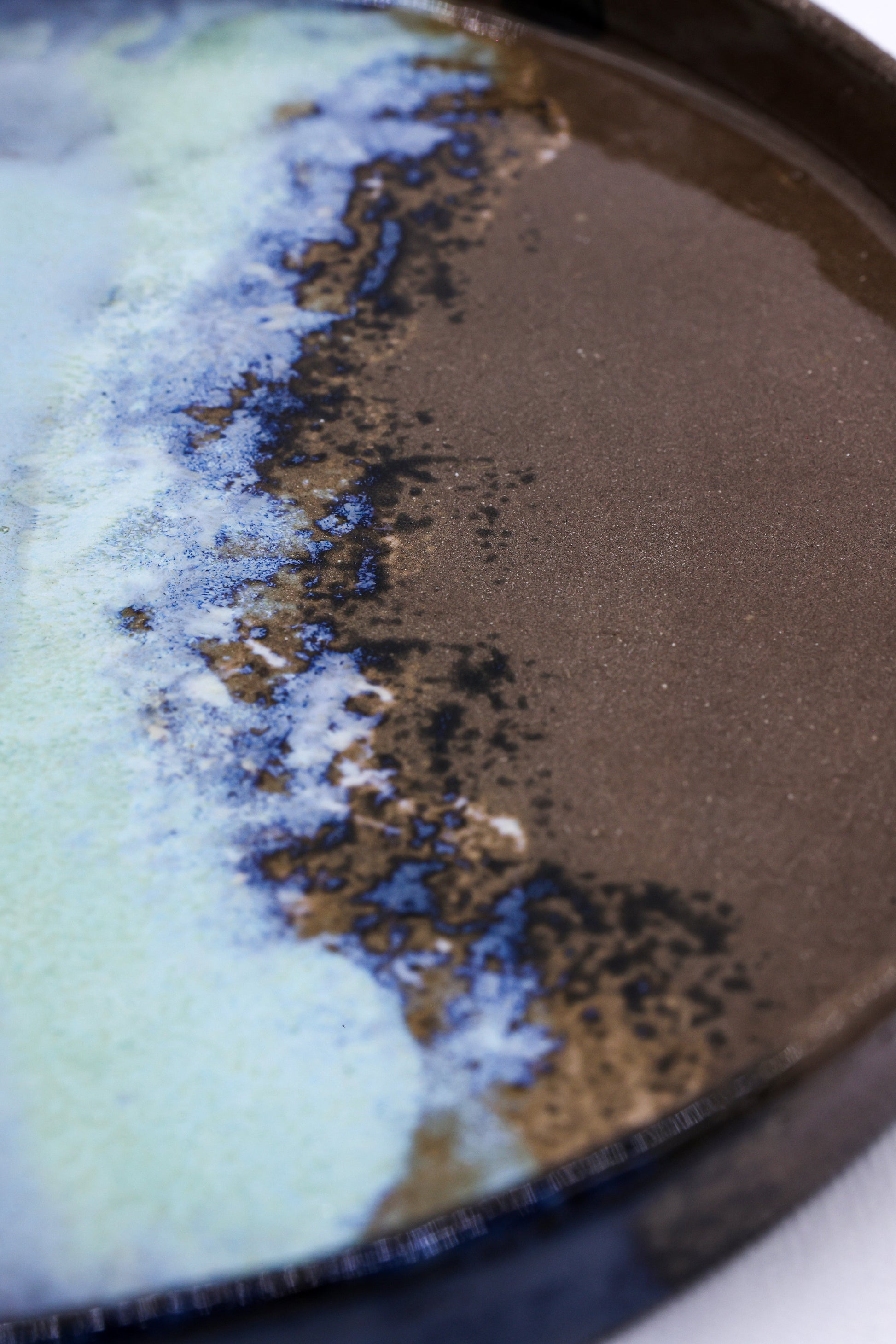 Handcrafted ceramic plate with earthy brown and ocean blue glaze, perfect for van life dining essentials.