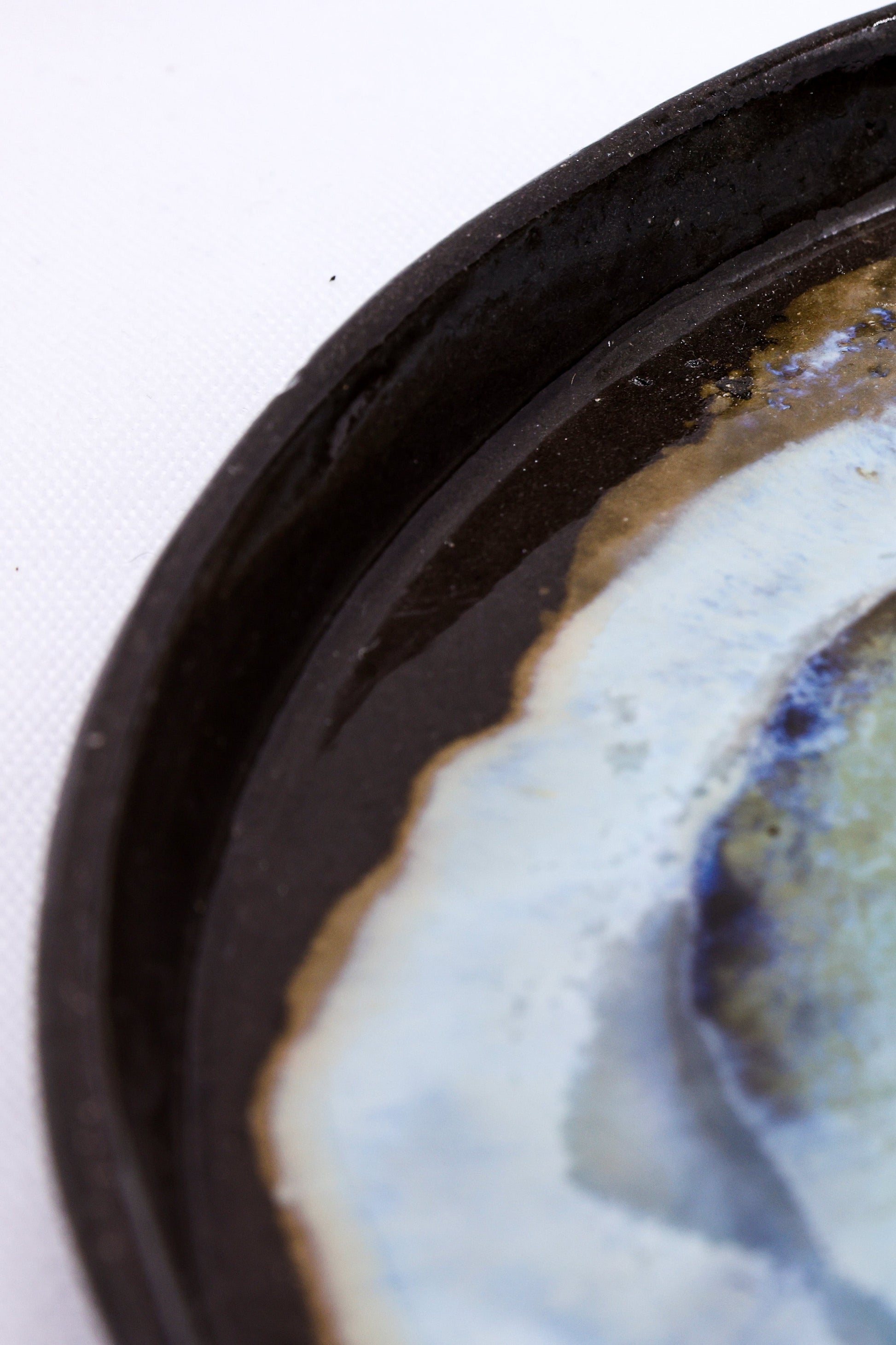 Handcrafted ceramic bowl with black rim and blue-white glaze, perfect for van life camping essentials.