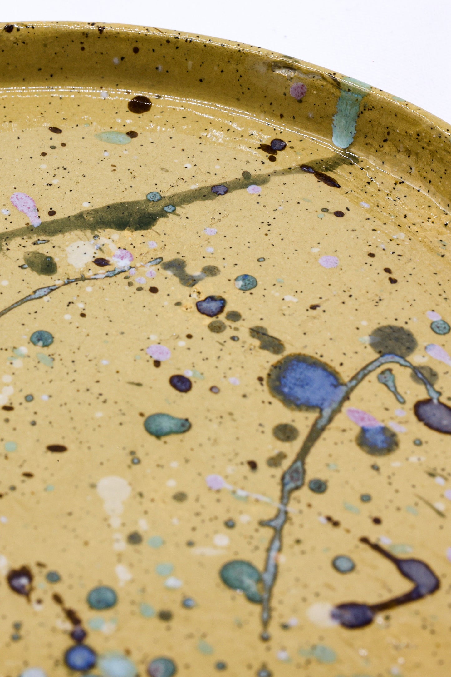 Handmade ceramic plate with speckled glaze and abstract blue, pink, green splatters, perfect for van life dining.