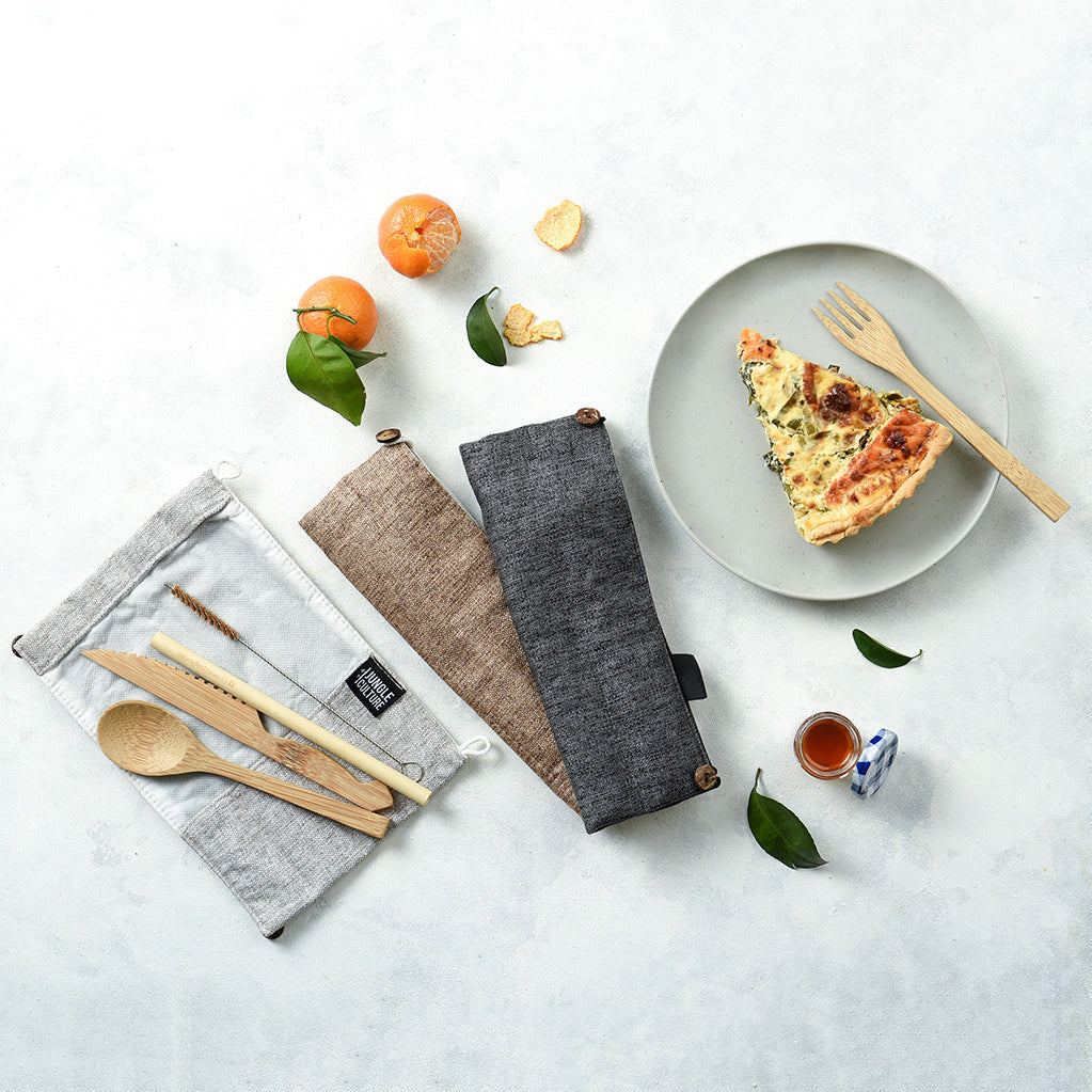 Bamboo cutlery set in fabric pouches with quiche and oranges, perfect for van life and outdoor adventures