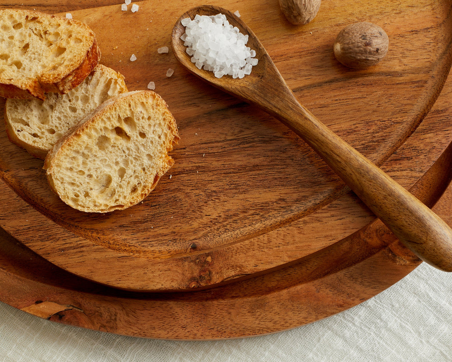 Wooden cutting board with sliced bread, salt spoon, and nutmeg for van life kitchen essentials