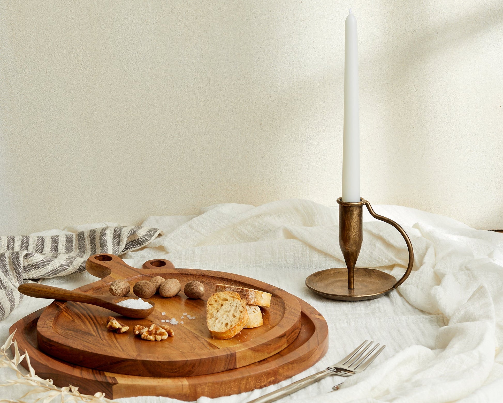 Wooden serving board with bread, nuts, salt, and brass candlestick for van life kitchen essentials