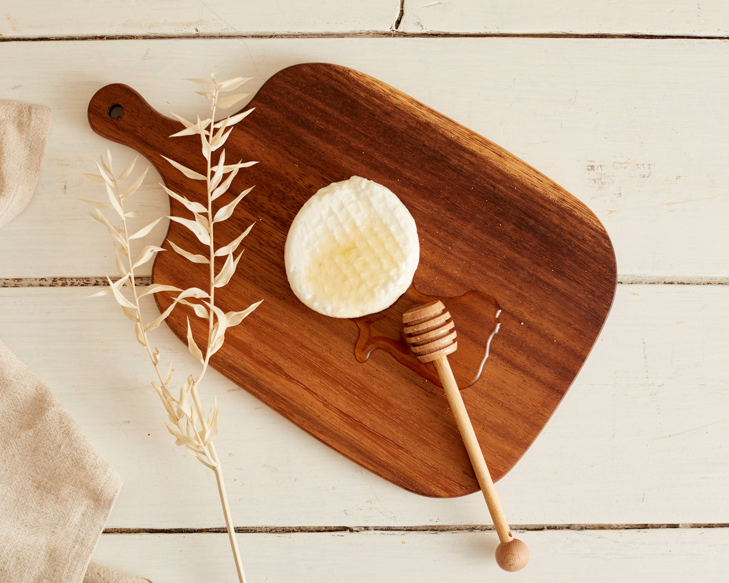 Wooden cutting board with cheese, honey drizzle, and honey dipper — perfect for van life snacks and outdoor adventures.