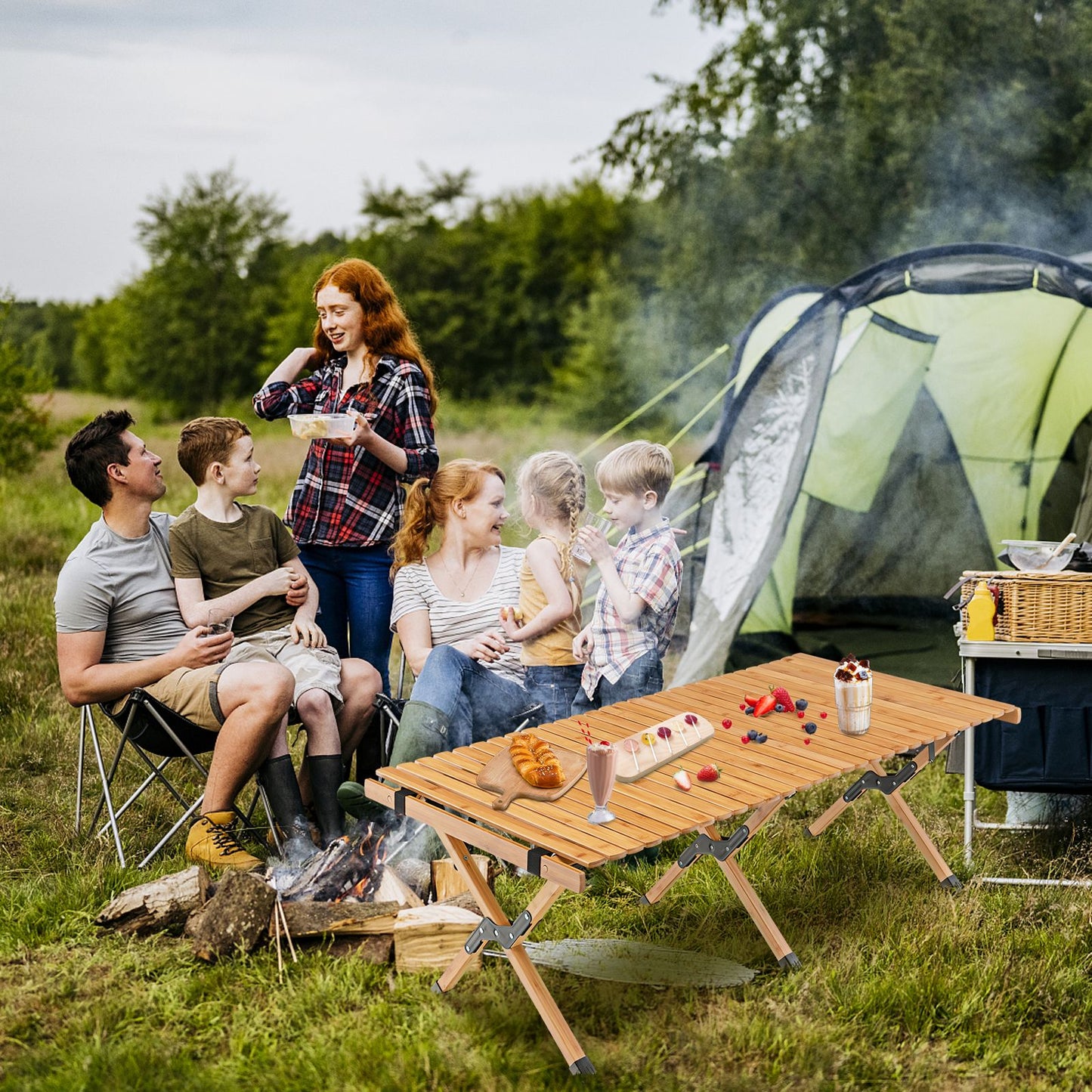 Portable bamboo camping table with family enjoying outdoor meal near tent and campfire