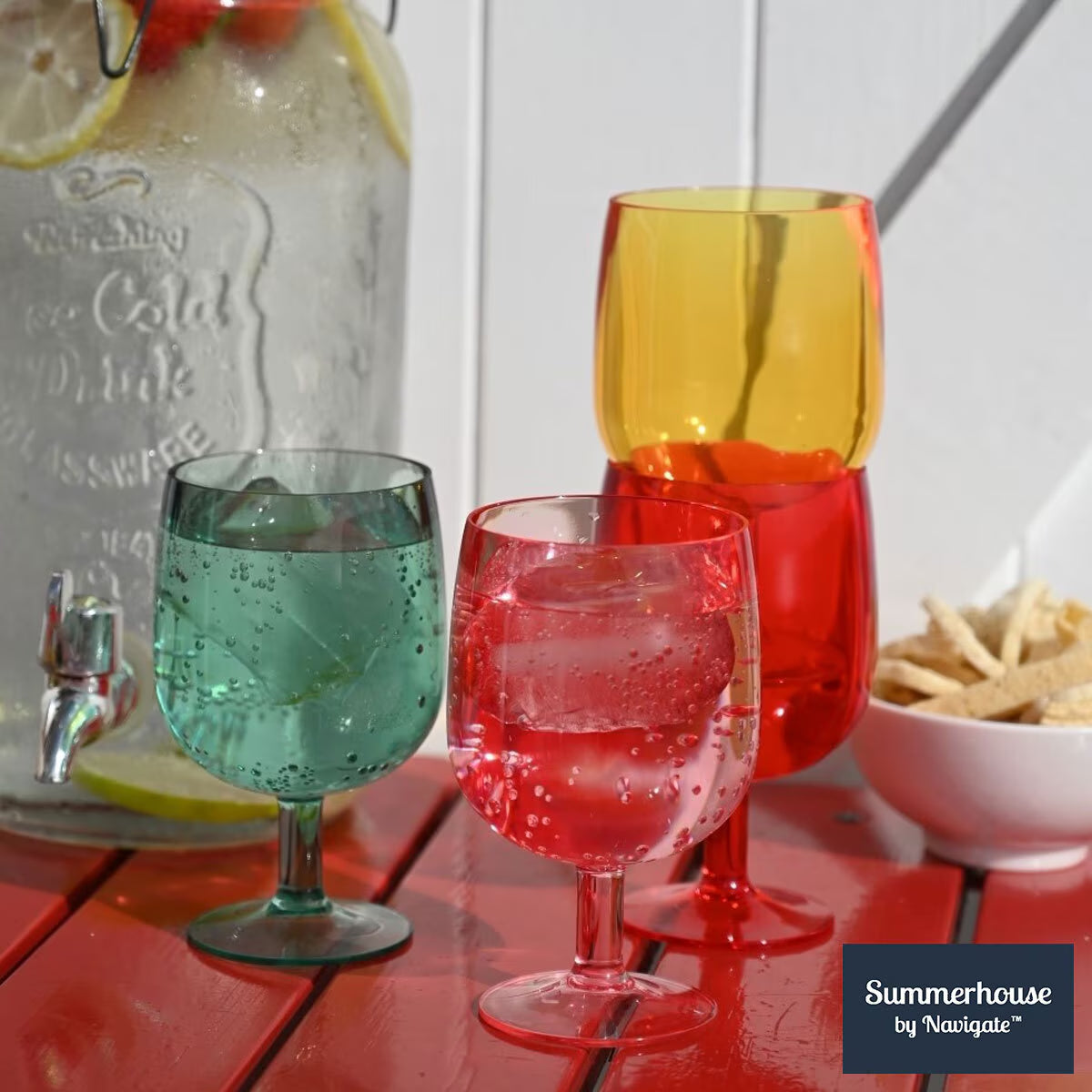 Colorful stemware glasses with fizzy drinks on red table, perfect for van life adventures and outdoor gatherings.