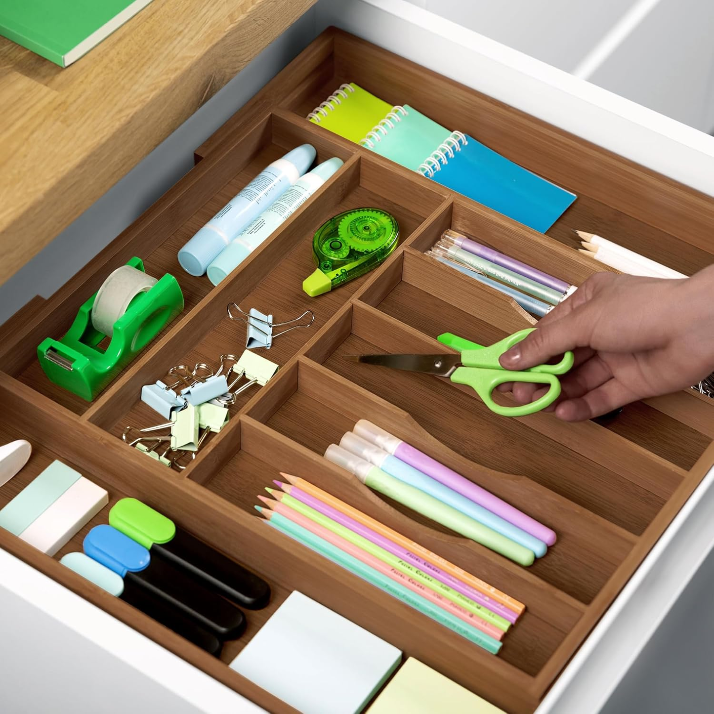 Wooden drawer organizer with compartments for pens, scissors, tape, and notebooks, perfect for van life storage.