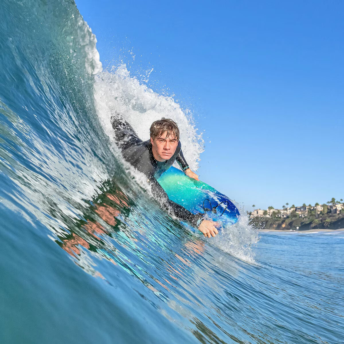 Man surfing on blue wave with bodyboard, ocean adventure gear for van life travelers