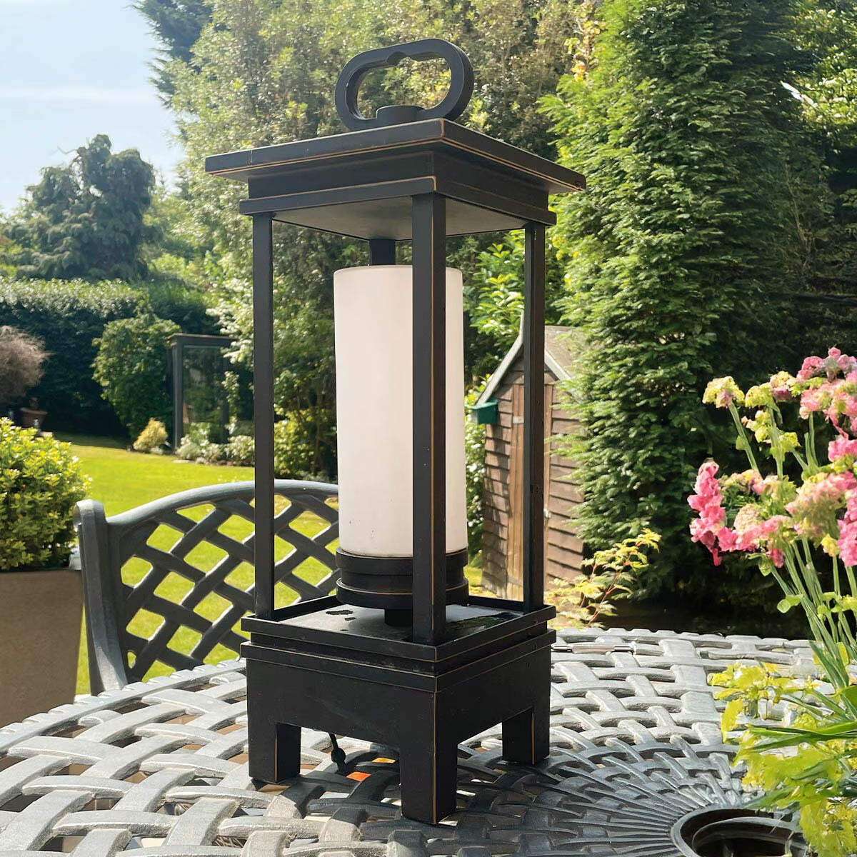 Black outdoor lantern with white diffuser on patio table, perfect for van life camping and garden evenings