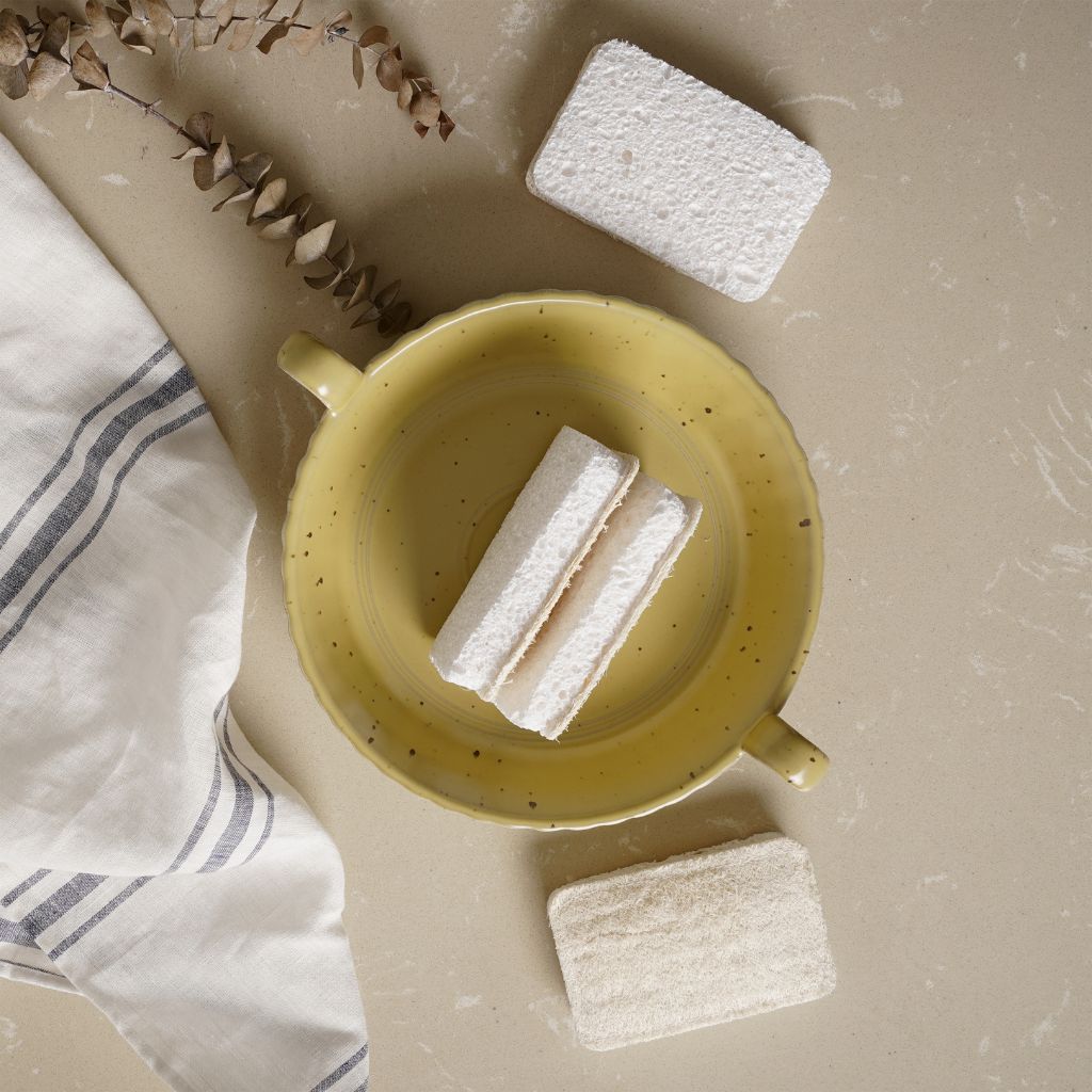 Natural sponge scrubbers in yellow ceramic dish with striped towel, ideal for van life kitchen cleaning