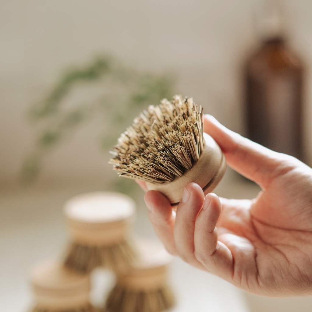 Hand holding natural bristle dish brush for van life kitchen cleaning