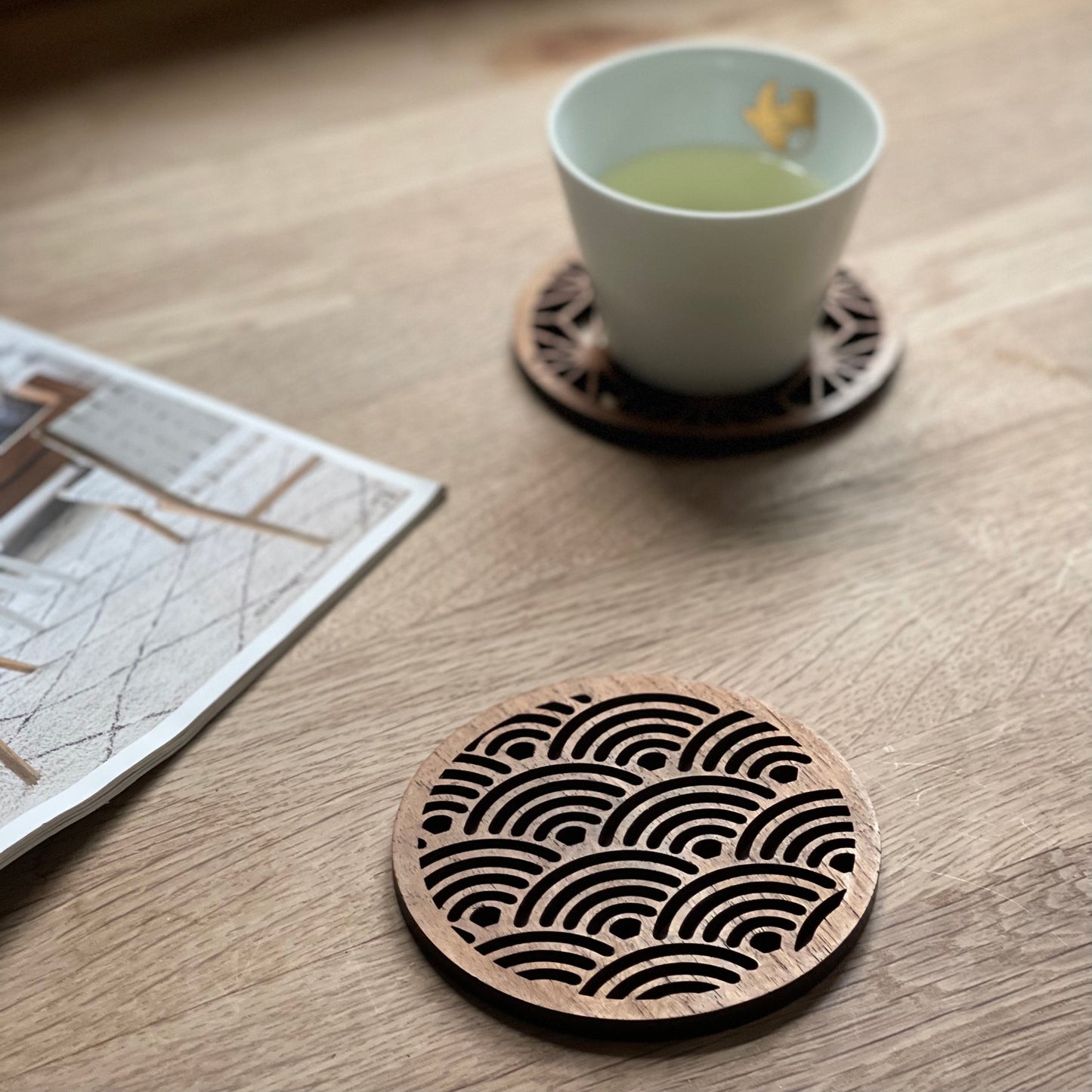 Wooden wave-patterned coasters for van life, paired with tea cup on wooden table