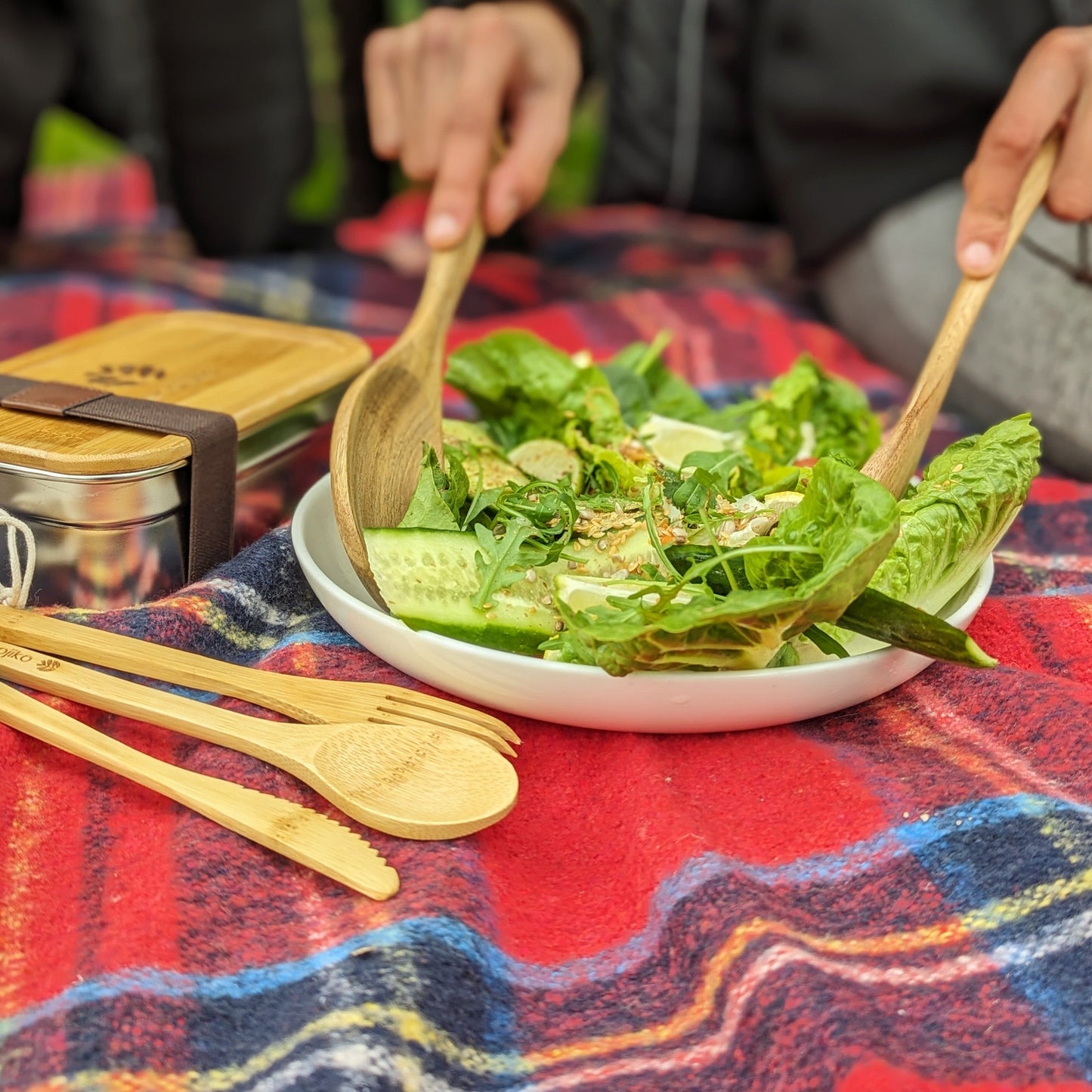 Bamboo salad servers and cutlery on plaid blanket for van life picnics and outdoor adventures