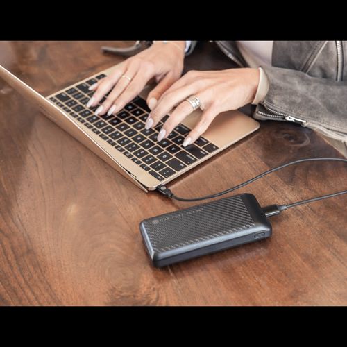 Portable power bank charging laptop on wooden table, ideal for van life and outdoor adventures